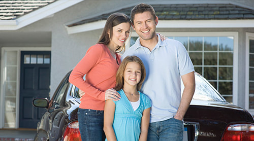 Happy parent together with their daughter standing behind their car and house photo